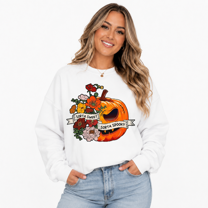 Woman styling white floral pumpkin sweatshirt with Sorta Sweet Sorta Spooky graphic and light blue jeans in studio.
