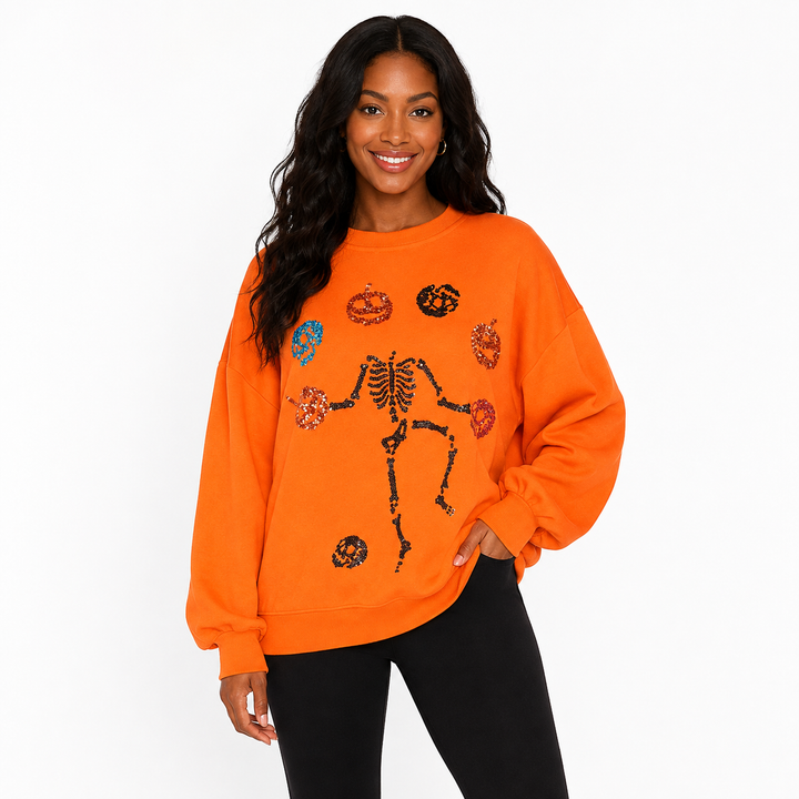 Halloween sweatshirt for women in orange with skeleton pumpkin sequin detail, front view on a white studio background visual.