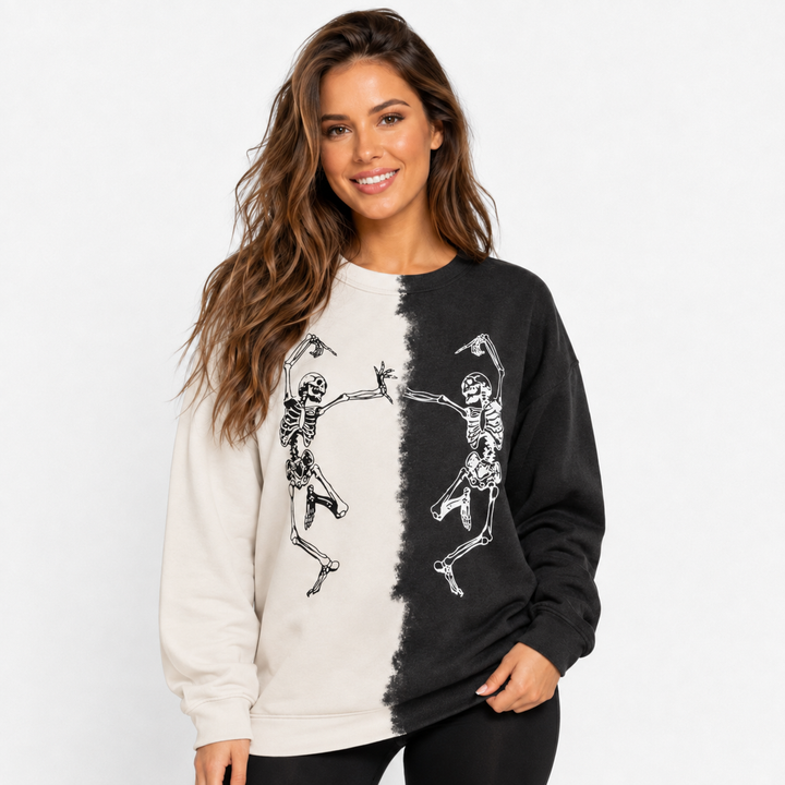 Woman wearing ivory and black Halloween skeleton sweatshirt with dancing skeleton print in a clean close studio view.