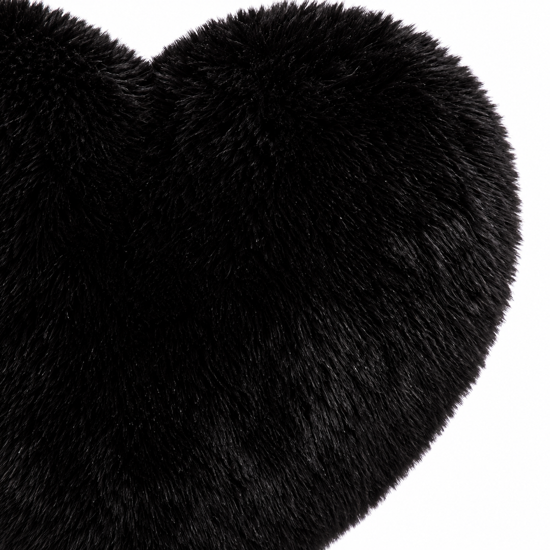 Close-up of the black plush heart bag showing the textured exterior, stitched center and curved top of its heart-shaped body.