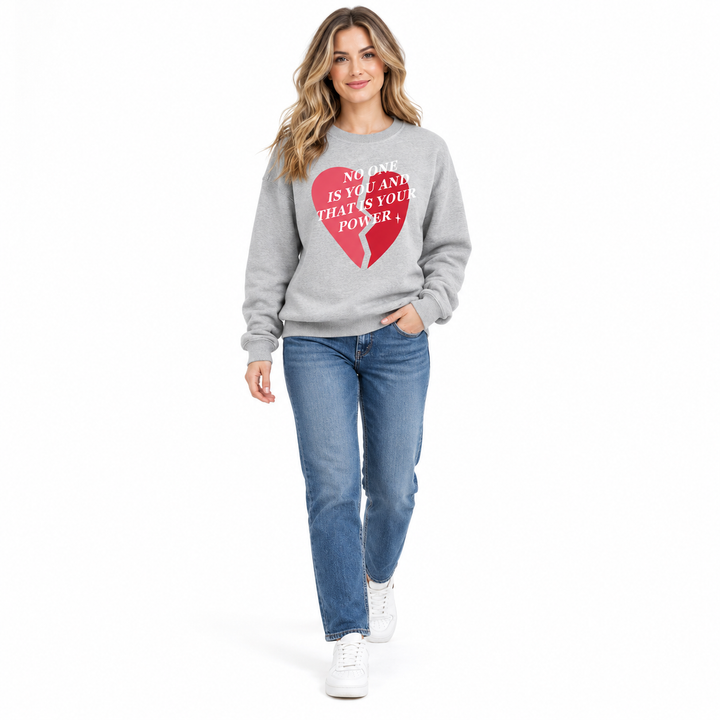 Gray printed sweatshirt on a full-length female model stepping forward in jeans and trainers against a white studio backdrop.