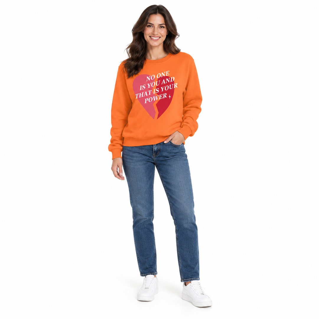 Orange sweatshirt on a second full-length female model with dark blue jeans and white trainers against white studio backdrop.