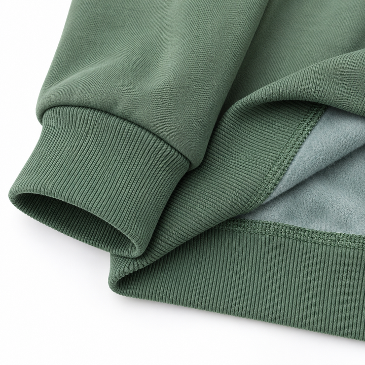 Olive green sweatshirt detail showing the ribbed cuff, folded hem, inner fleece surface and stitching against white backdrop.