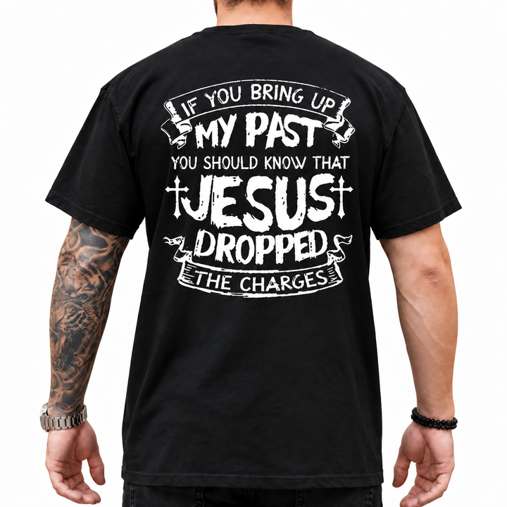 Black Christian graphic T-shirt with distressed JESUS DROPPED THE CHARGES back print shown on a male model in a white studio.
