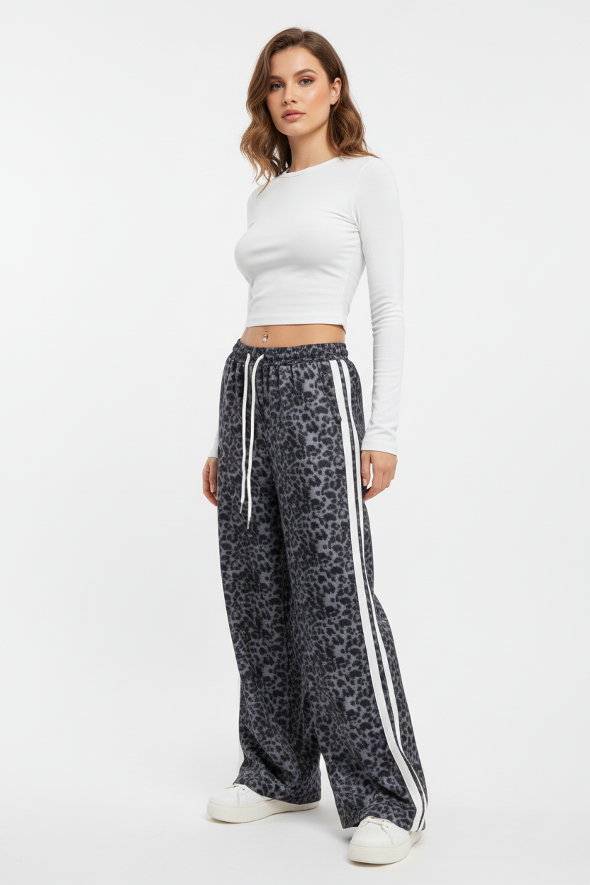 Woman wearing a white long-sleeve top and leopard print pants with white stripes on a white background