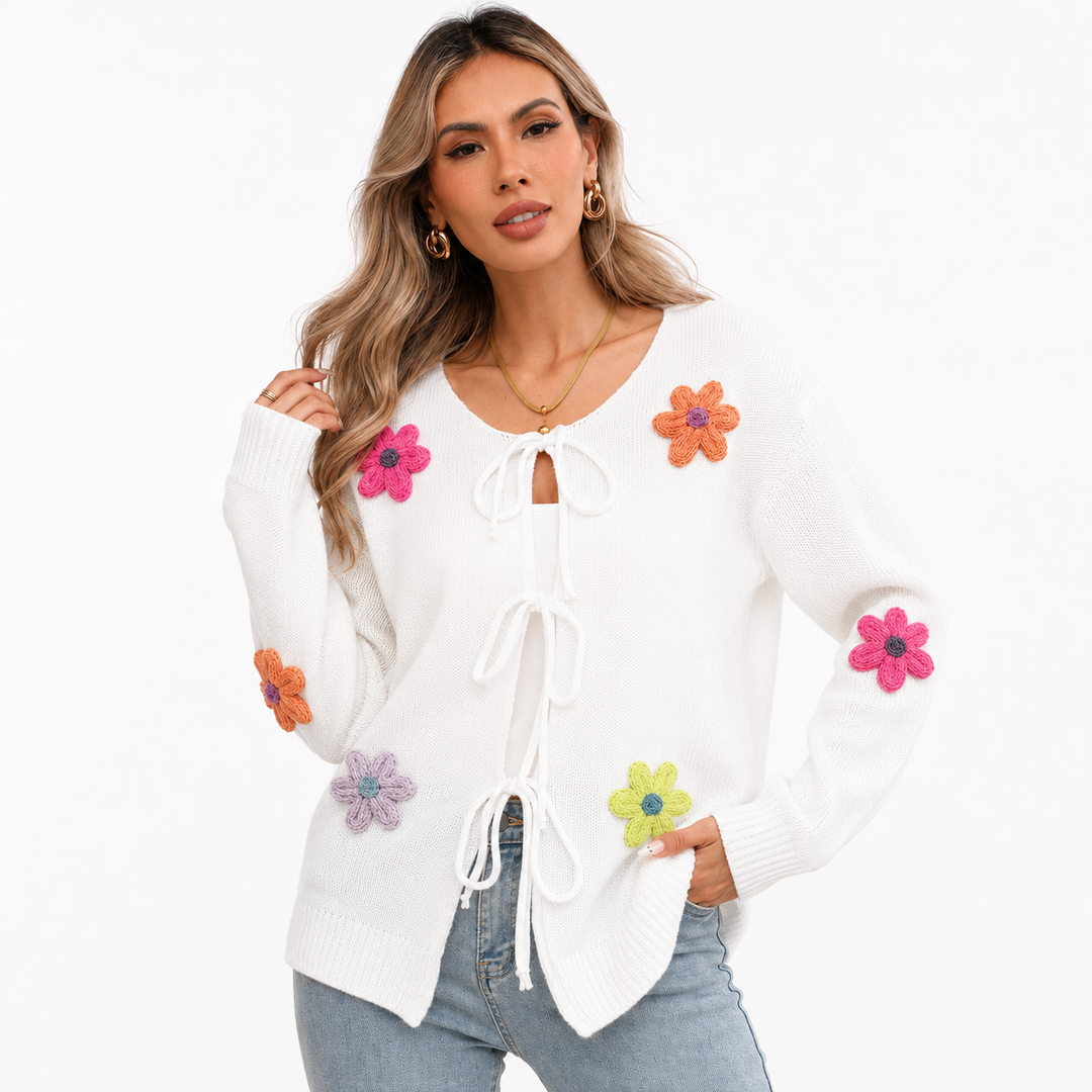 White floral tie-front knit cardigan close view on a woman, showing knit texture, colorful flower appliques and bow closures.