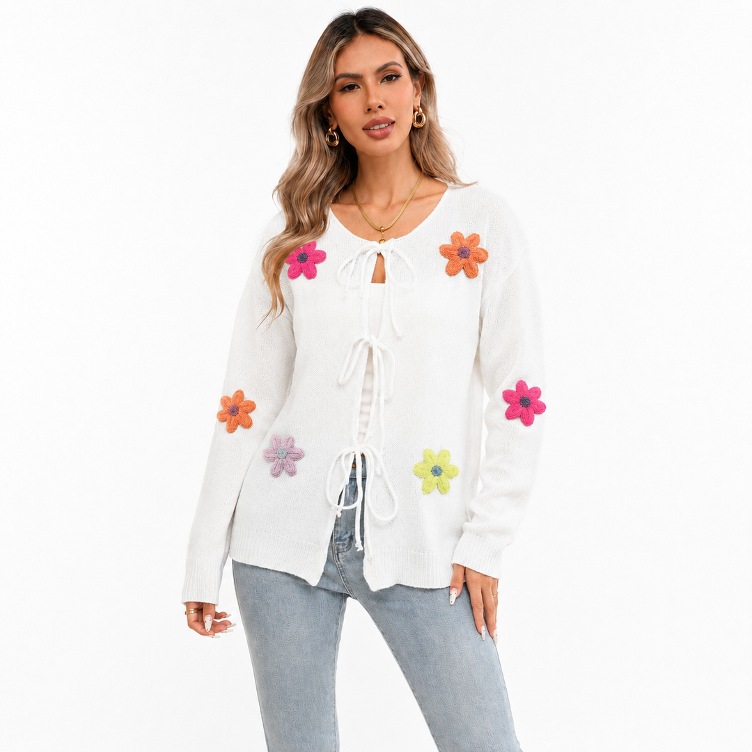 White floral tie-front knit cardigan on a woman with visible face, front bow closures, long sleeves and colorful flower appliques.