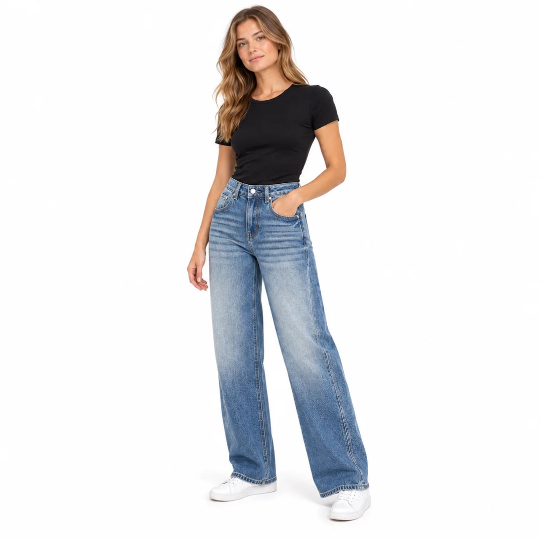 Light blue wide leg jeans on a woman wearing a black T-shirt and white sneakers, shown in a three-quarter front studio image.