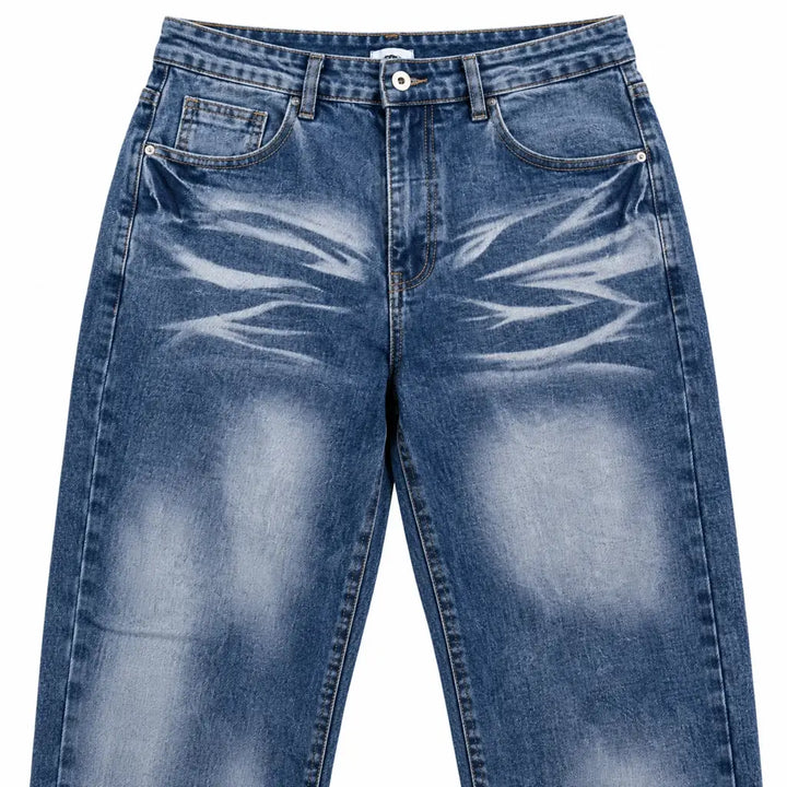 Close-up of blue denim jeans showing front waistband, coin pocket, rivets, stitching, faded thighs and curved whisker design.