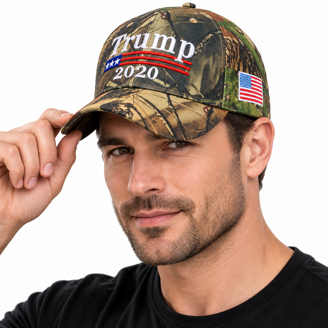 Male model wearing a camouflage embroidered baseball cap with front lettering and a US flag side patch.