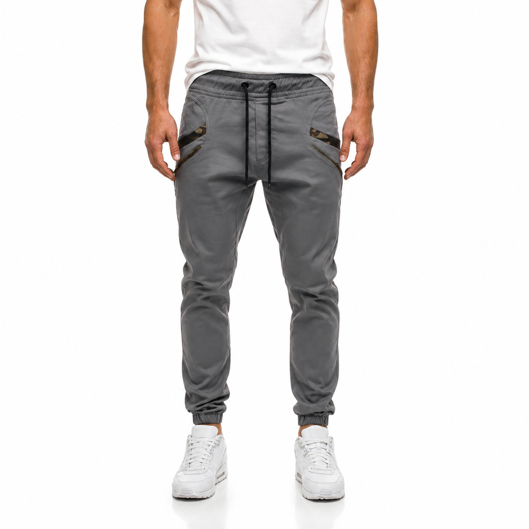 Grey slim jogger pants for men shown from the front with tapered legs, camouflage pocket trim and casual styling in full view
