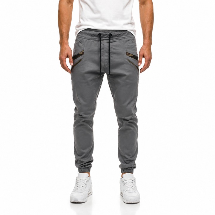 Grey slim jogger pants for men shown from the front with tapered legs, camouflage pocket trim and casual styling in full view
