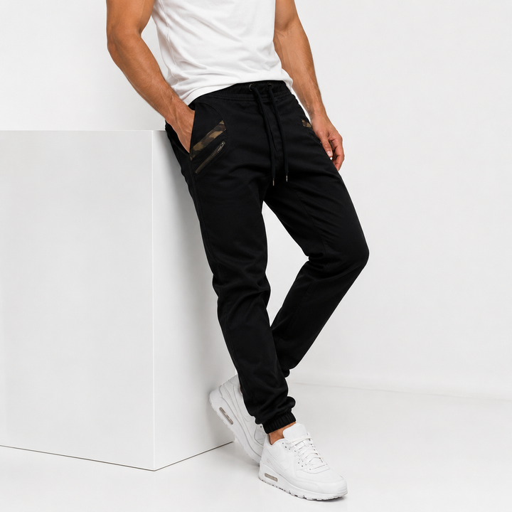 Black slim jogger pants for men shown in a full front fit view with tapered legs, elastic cuffs and pocket details front view