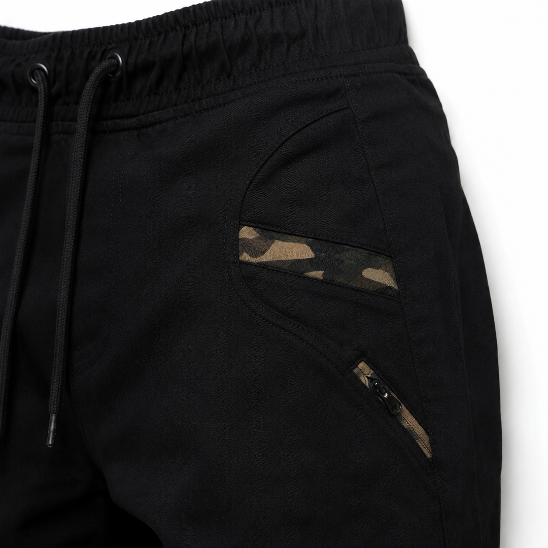 Black jogger pants close-up showing camouflage pocket trim, zipper detail, stitching and cotton blend fabric texture fit view