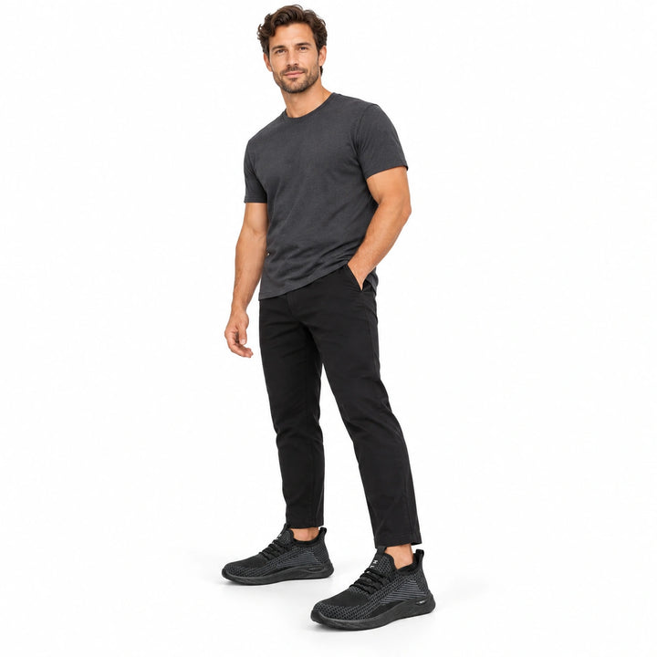 Male model wearing Black Style 1 knit shoes with black trousers in a white studio.