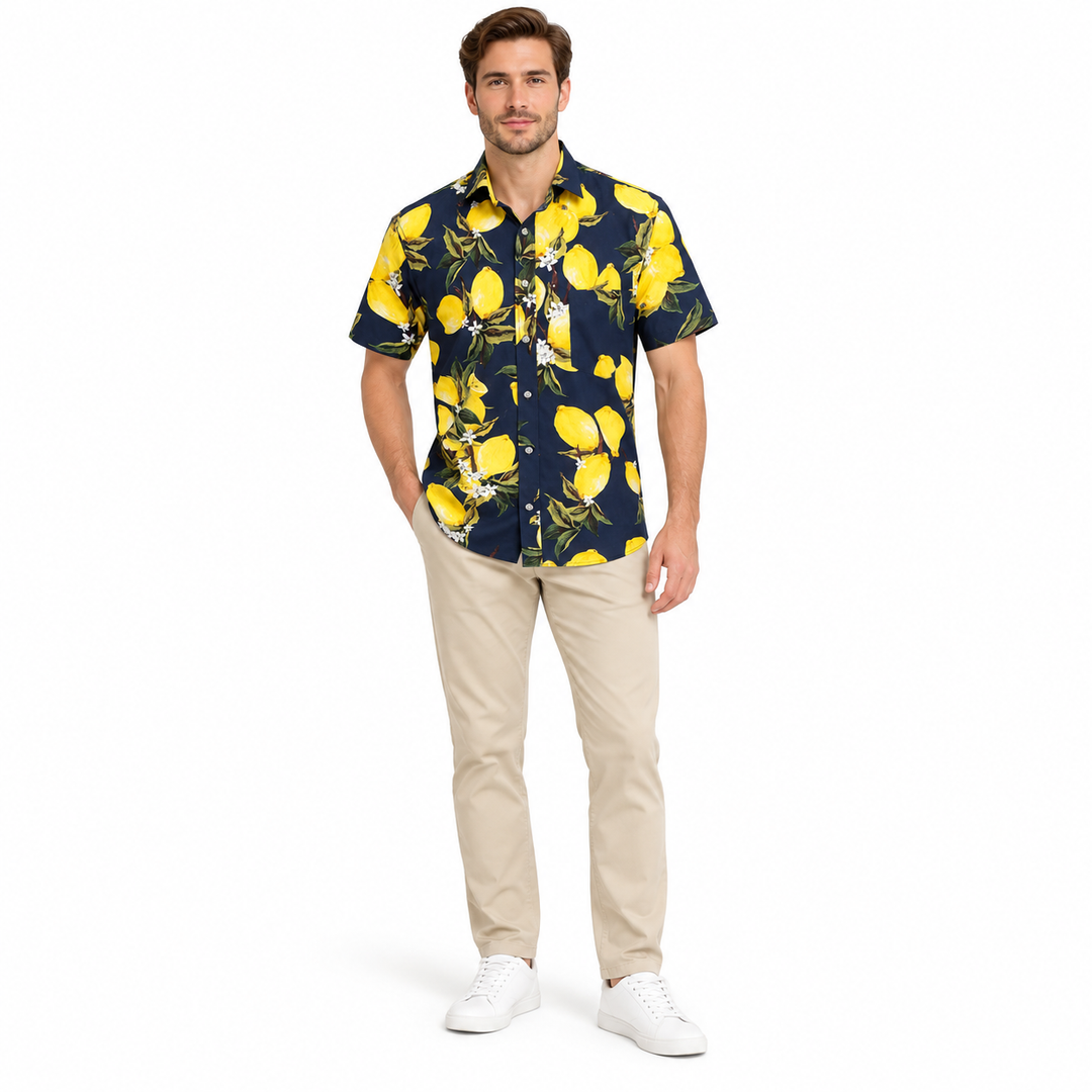 Model wearing a navy fruit print shirt in a full-body front view with trousers and shoes visible on a plain white background.