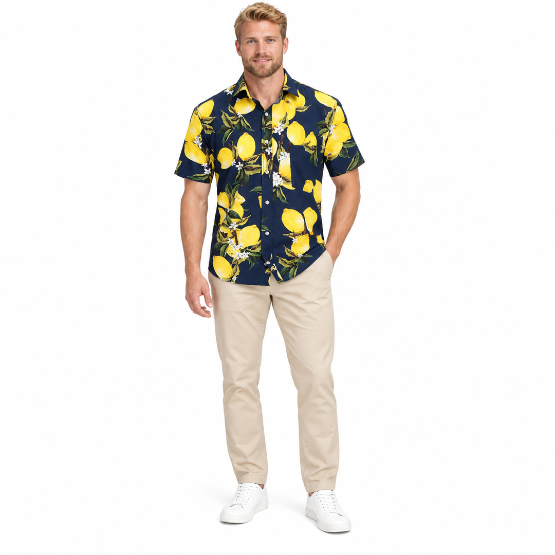 Model wearing a navy fruit print shirt in a full-body front view with trousers and shoes visible on a plain white background.