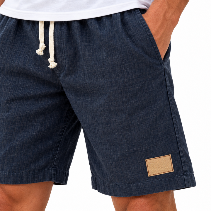 Close-up of navy shorts side pocket, seam stitching and blank hem patch