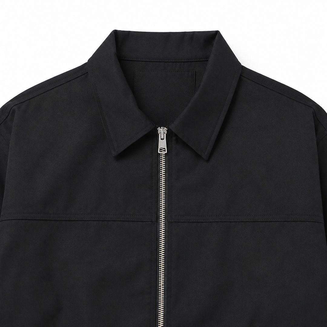 Black jacket collar and zipper detail with a fold-down shape, silver hardware, smooth polyester exterior and exact yoke seam.