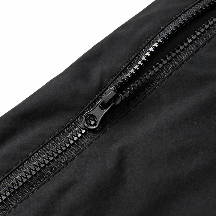 Close view of the black jacket zipper and surrounding fabric showing the metal slider and zipper teeth without supplier text.
