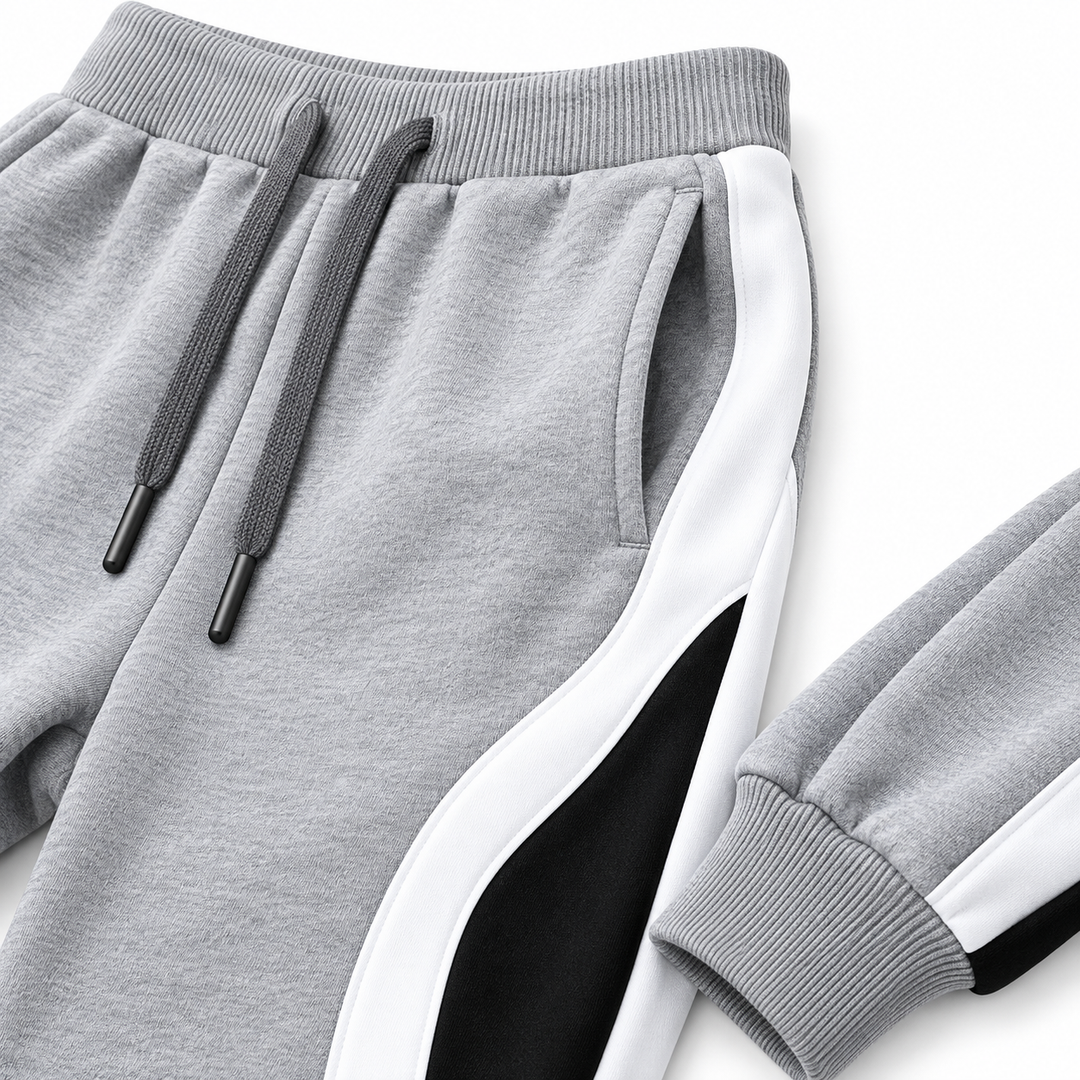 Close-up of Grey jogger pants showing the drawstring waist, pocket, curved side panel, stitching and ribbed cuff.