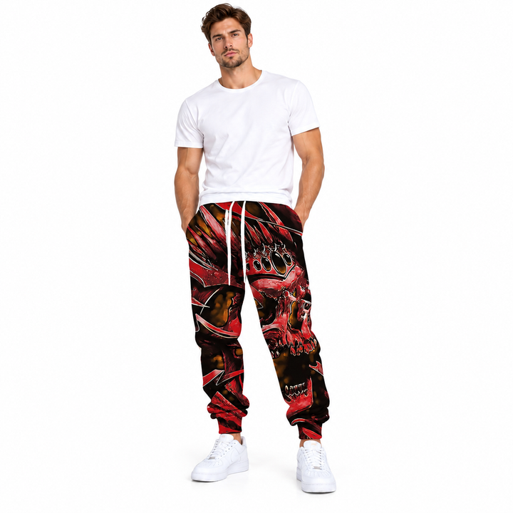 Male model wearing red crown skull printed pants, with a white T-shirt and white sneakers, against a white studio background.