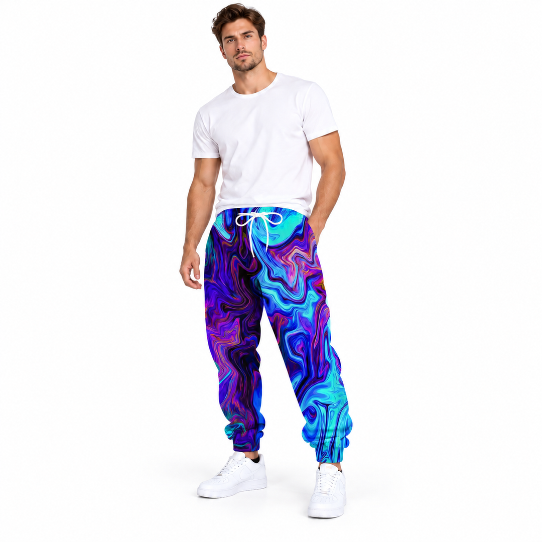 Male model wearing blue purple abstract printed pants, with a plain white tee and white sneakers, in a full-body studio view.