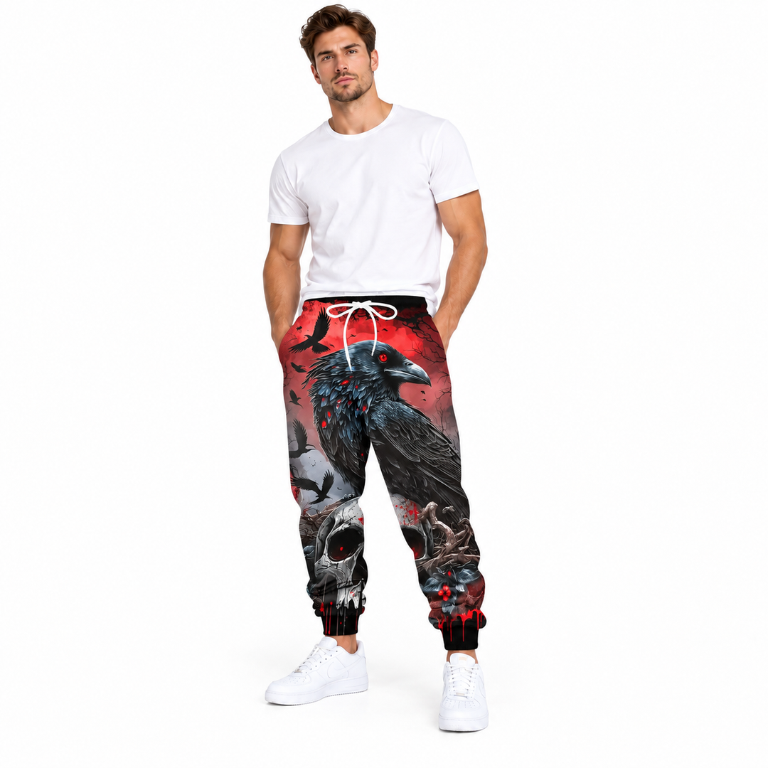 Male model wearing red raven and skull printed pants, with a white tee and white sneakers, against a white studio background.