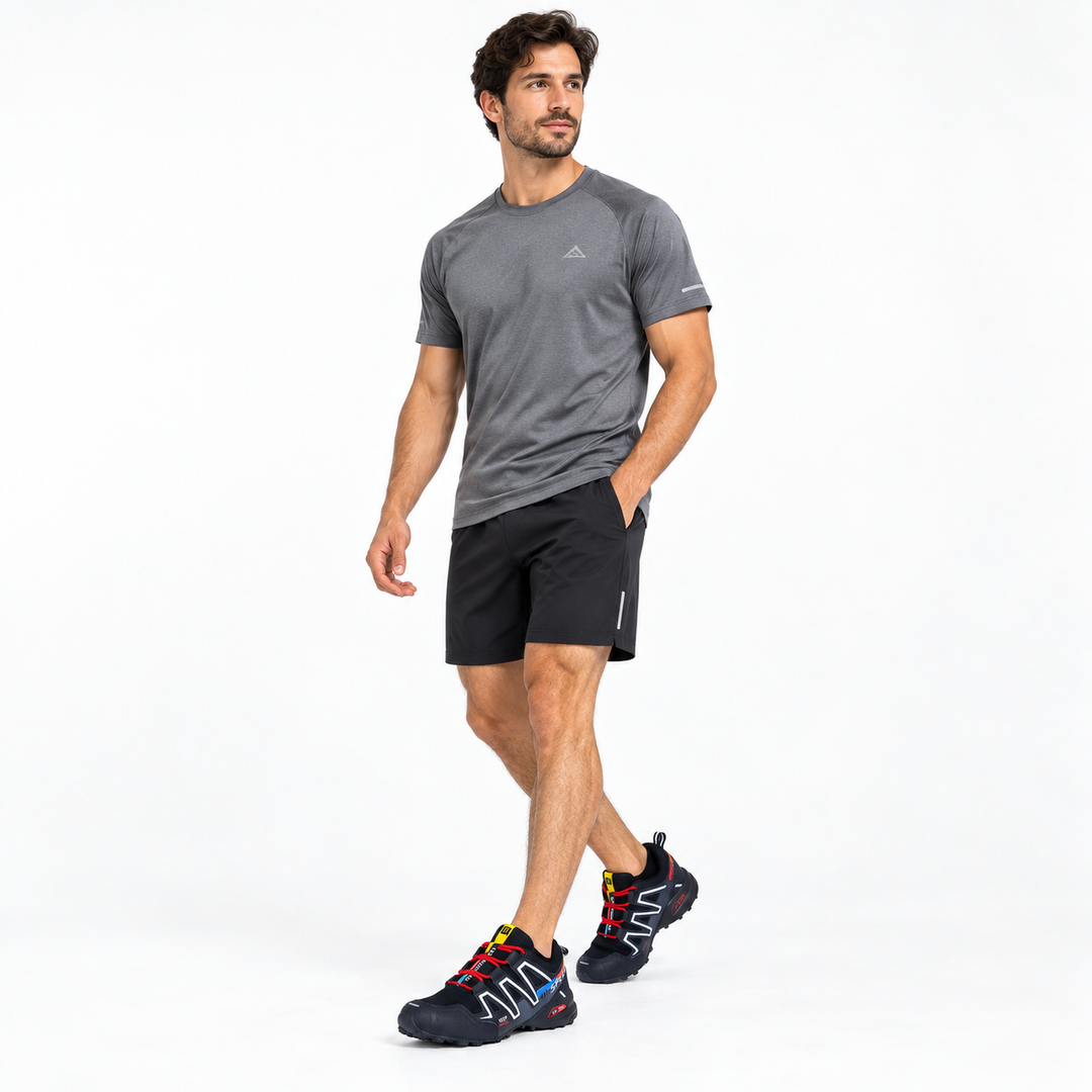 Male model wearing black trail running shoes in a full-body studio view
