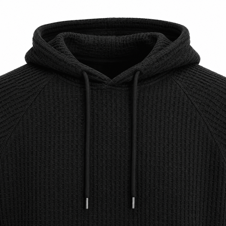 Black waffle knit hoodie close-up showing hood, drawstrings and raglan seam construction.