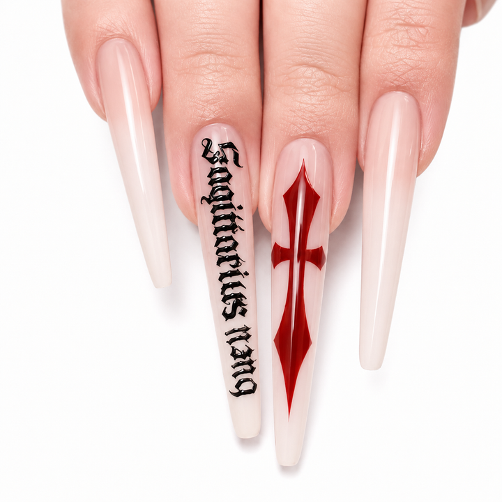 Close-up of milk white cross press on nails showing red cross accent, black gothic script artwork and glossy surface details.