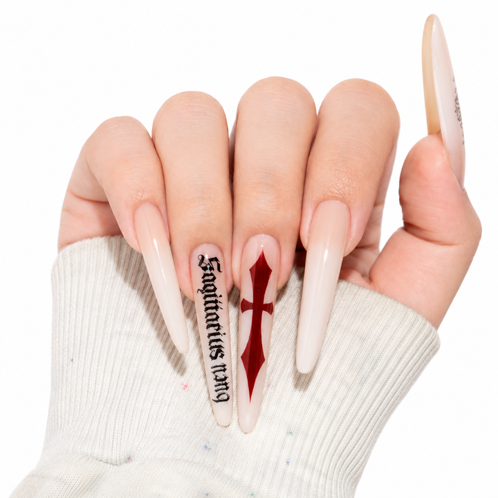 Press on nails kit display with milk white cross nail art, red accent, black gothic script and included tools on clean white.