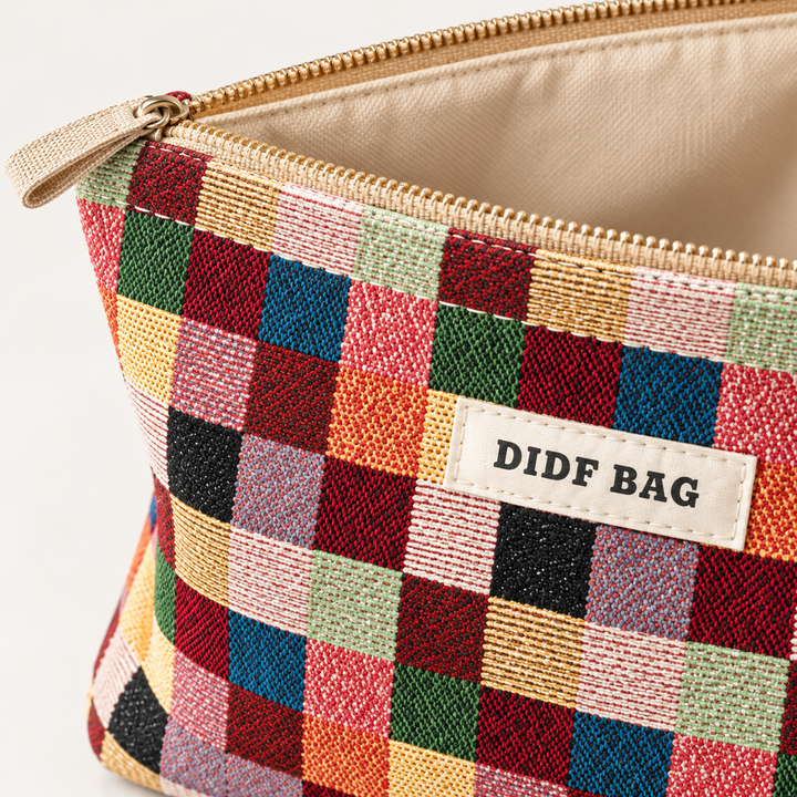 Close-up of Multicolor Plaid woven fabric, zipper, stitching and front label detail on the cosmetic bag.
