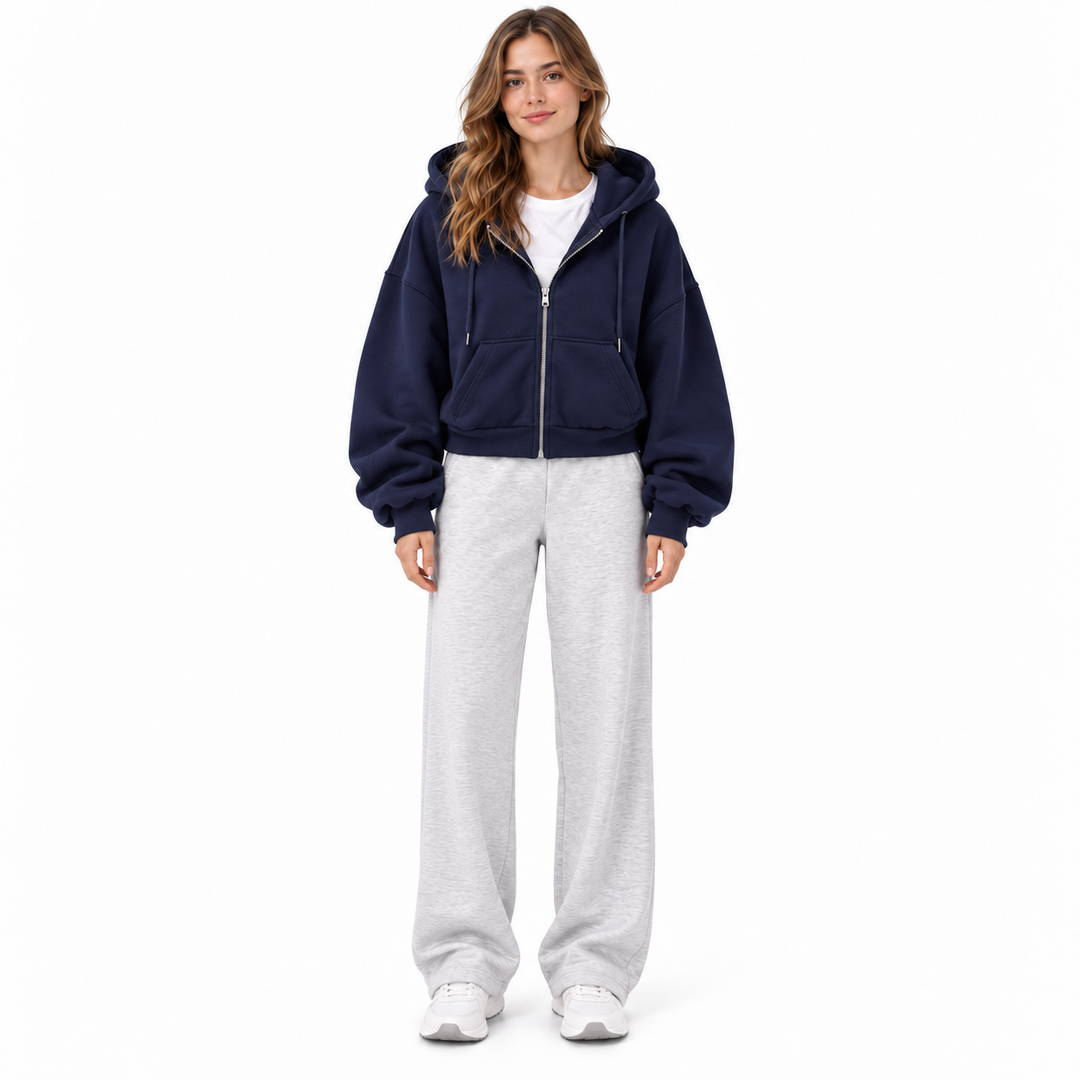 Photograph of navy cropped zip up hoodie in navy blue, straight front view, with long sleeves visible, on a white background.
