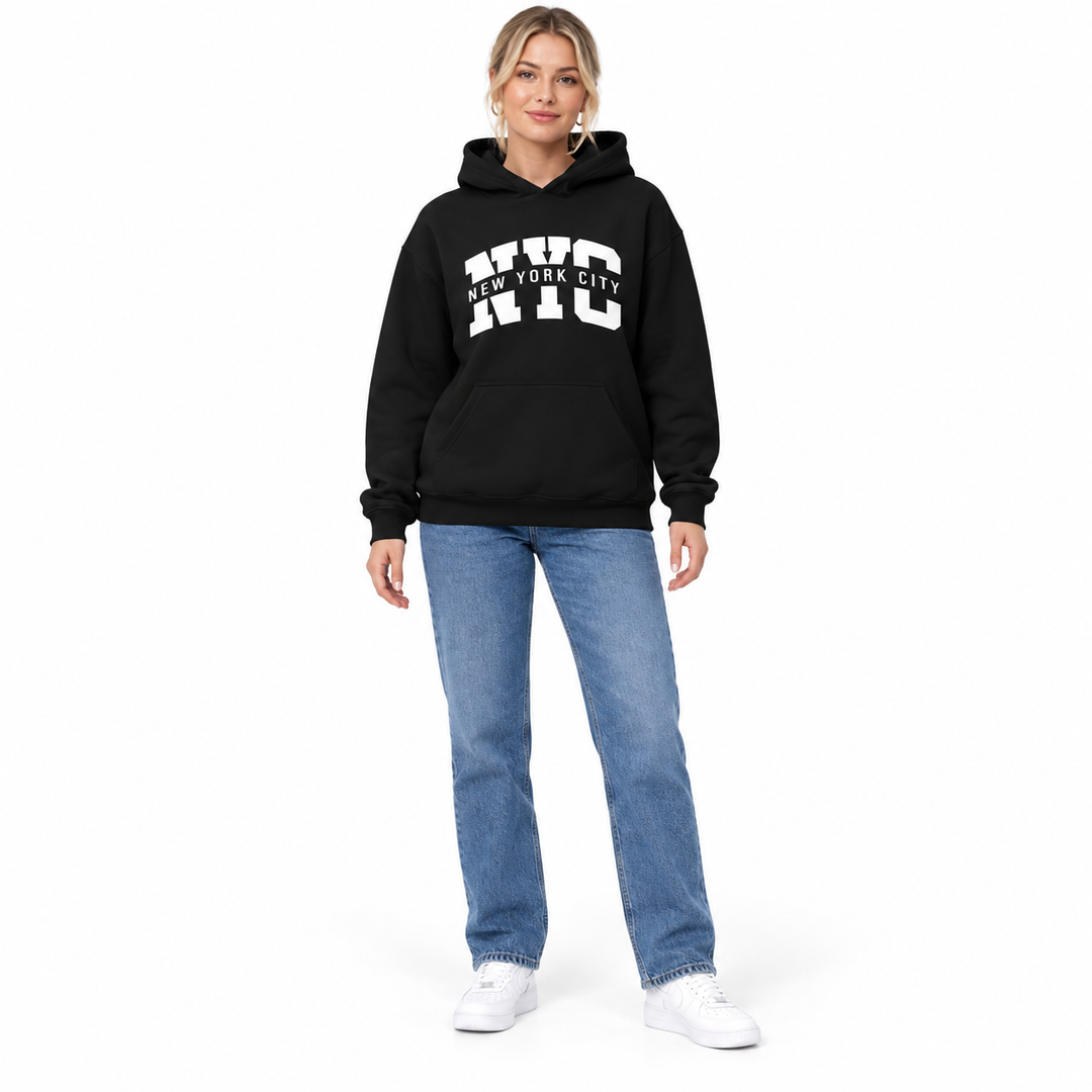 Full body model in a black hoodie with NYC City chest print, blue jeans and white sneakers against a white studio background.