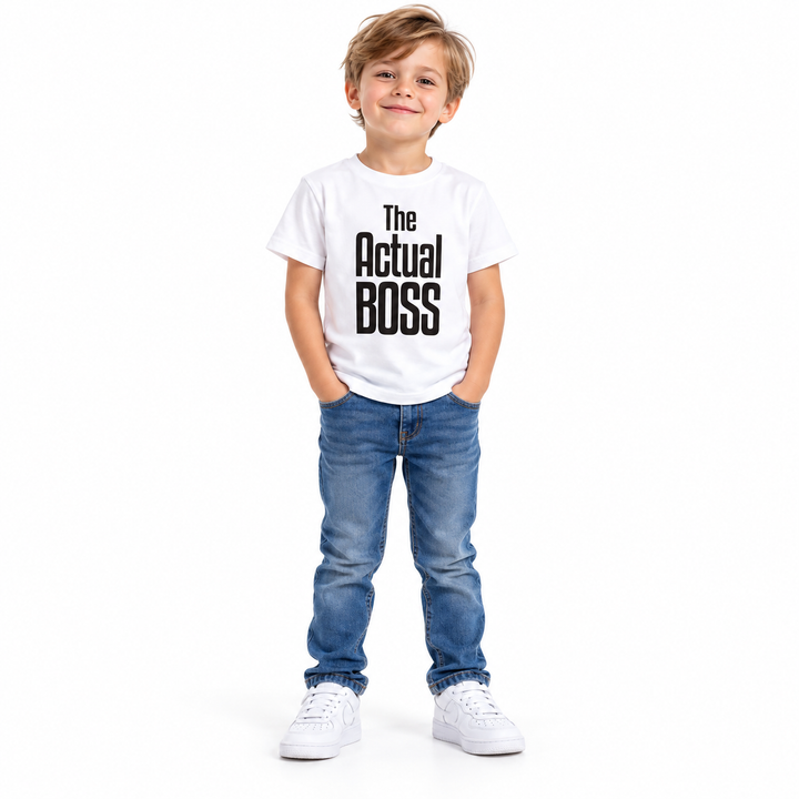 Full-body child wearing a white The Actual Boss printed T-shirt, blue jeans and white sneakers against white studio backdrop.