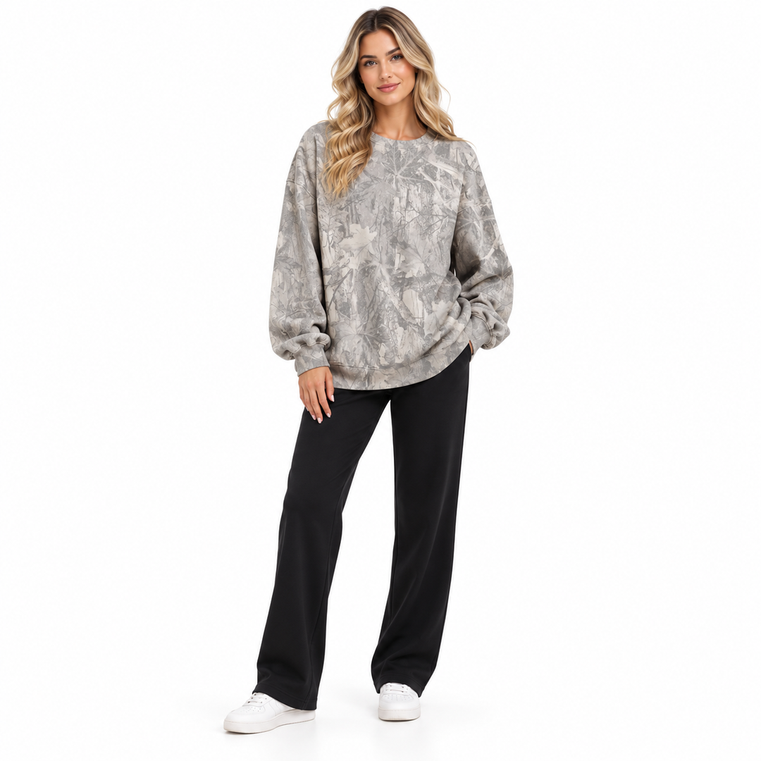 Model wearing a grey branch print sweatshirt shown standing from the front with sleeves visible on a seamless white backdrop.