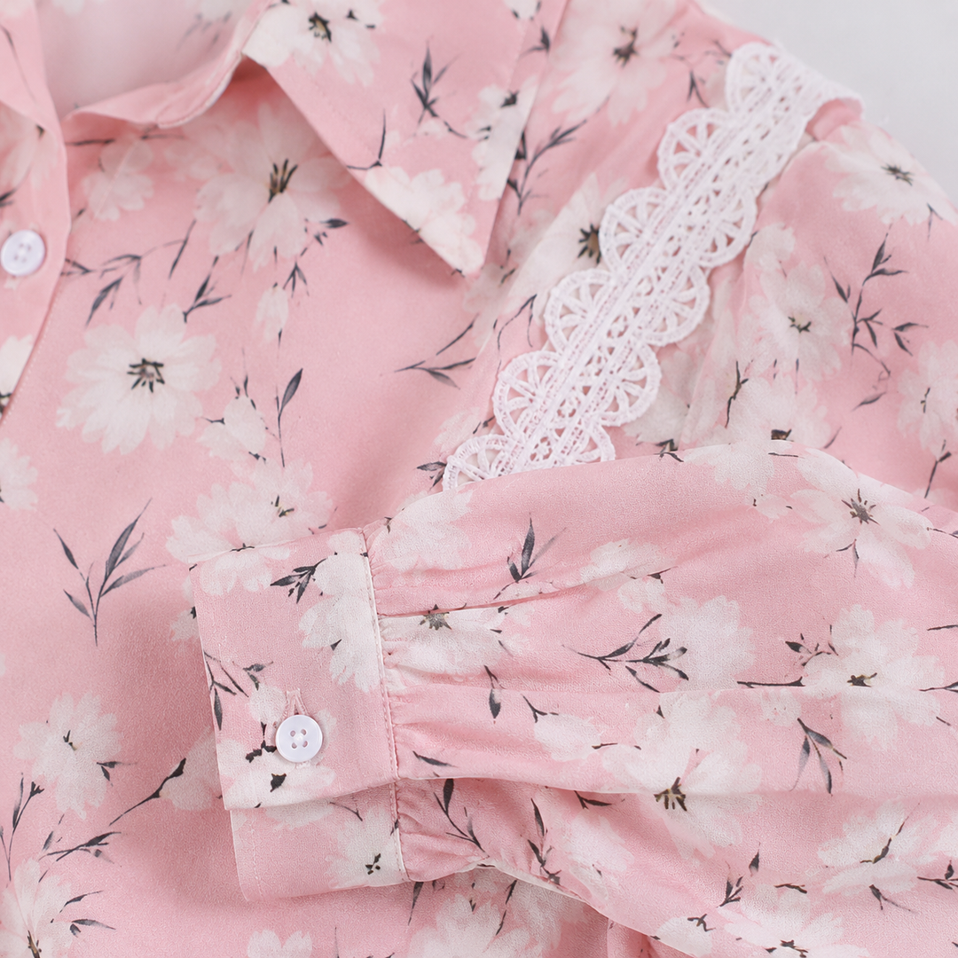 Close-up of the long sleeve and cuff showing floral fabric, white button, gathered stitching and decorative white lace trims.