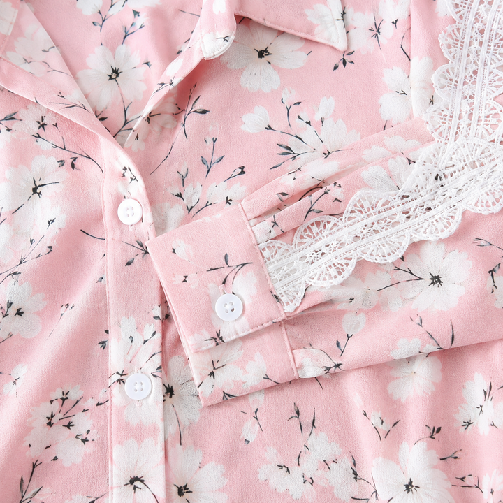 Macro detail of pink flower-print fabric with visible seams, collar, white buttons and decorative lace trim along the sleeve.