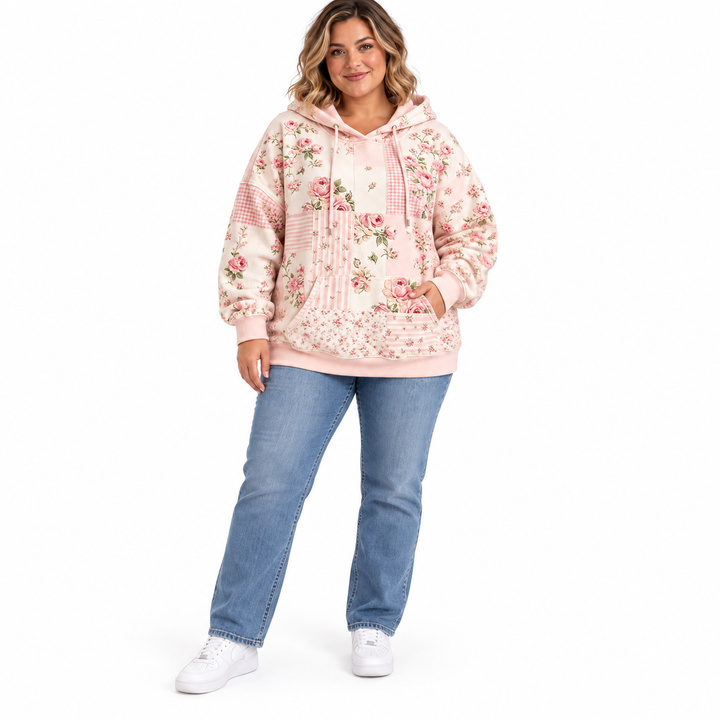 Plus size floral hoodie in blush pink on a model wearing blue jeans and white sneakers, full-length front view