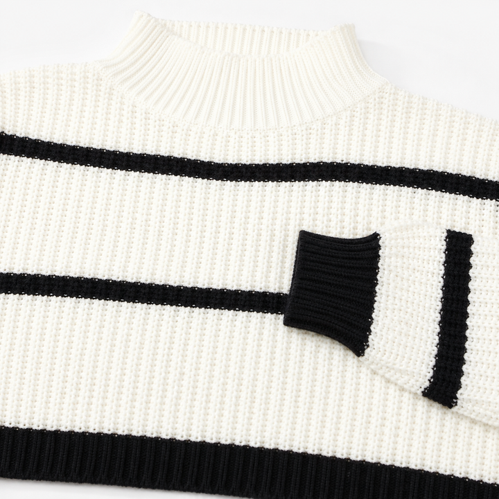 Detail view of the white sweater showing the ribbed mock neck, black cuff, stripe placement, and black ribbed hem finish.