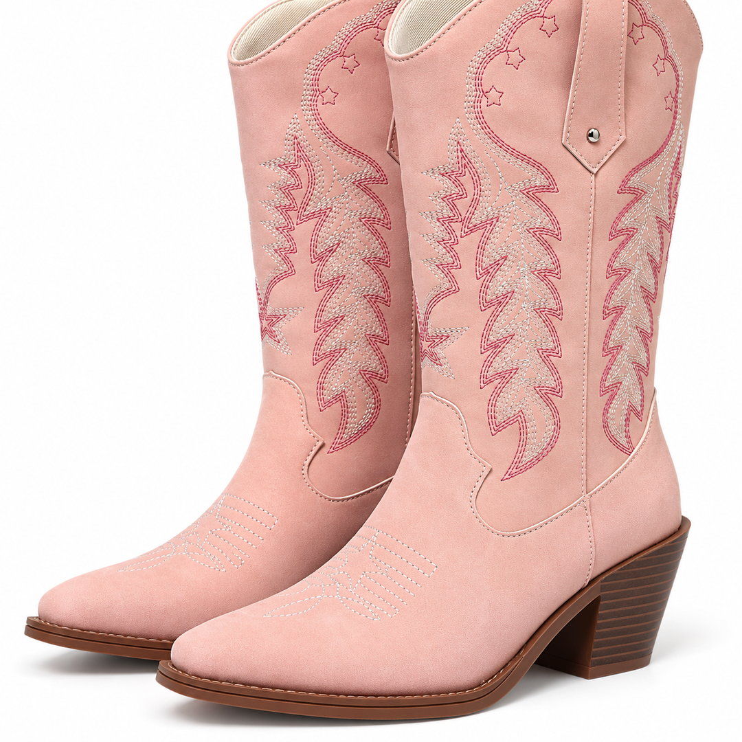 Close view of pink western boots with embroidered shafts, pointed toes and brown heels on a seamless white studio background.