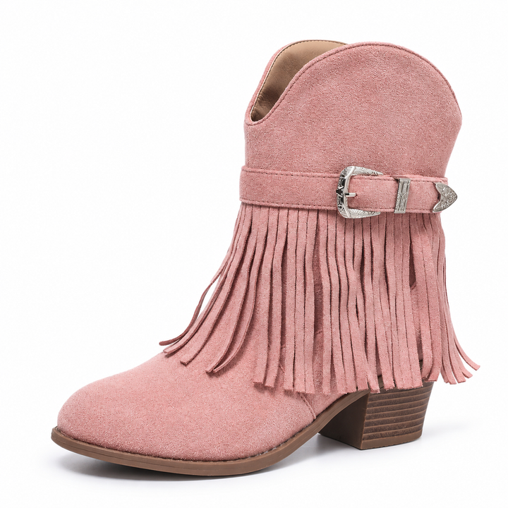 Three-quarter view of a pink fringe ankle boot with a silver buckle, fringe and a brown block heel in a white studio setting.