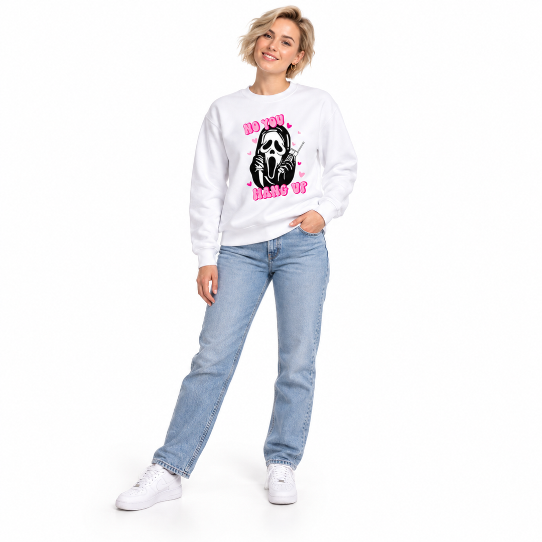 Woman wearing a white graphic pullover with pink lettering, a black phone graphic and ribbed cuffs in a white studio setting.