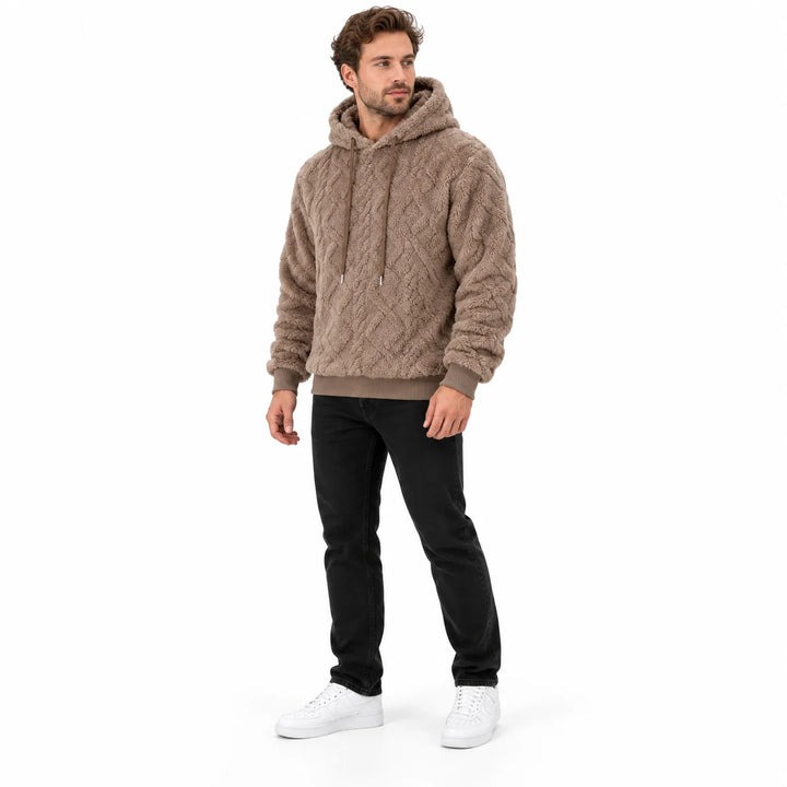Camel brown pullover shown at a three-quarter angle on a male model, displaying the hood, geometric texture and ribbed cuffs.