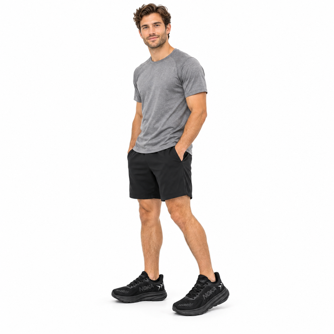 Male model wearing black lace-up sneakers on a white studio background.