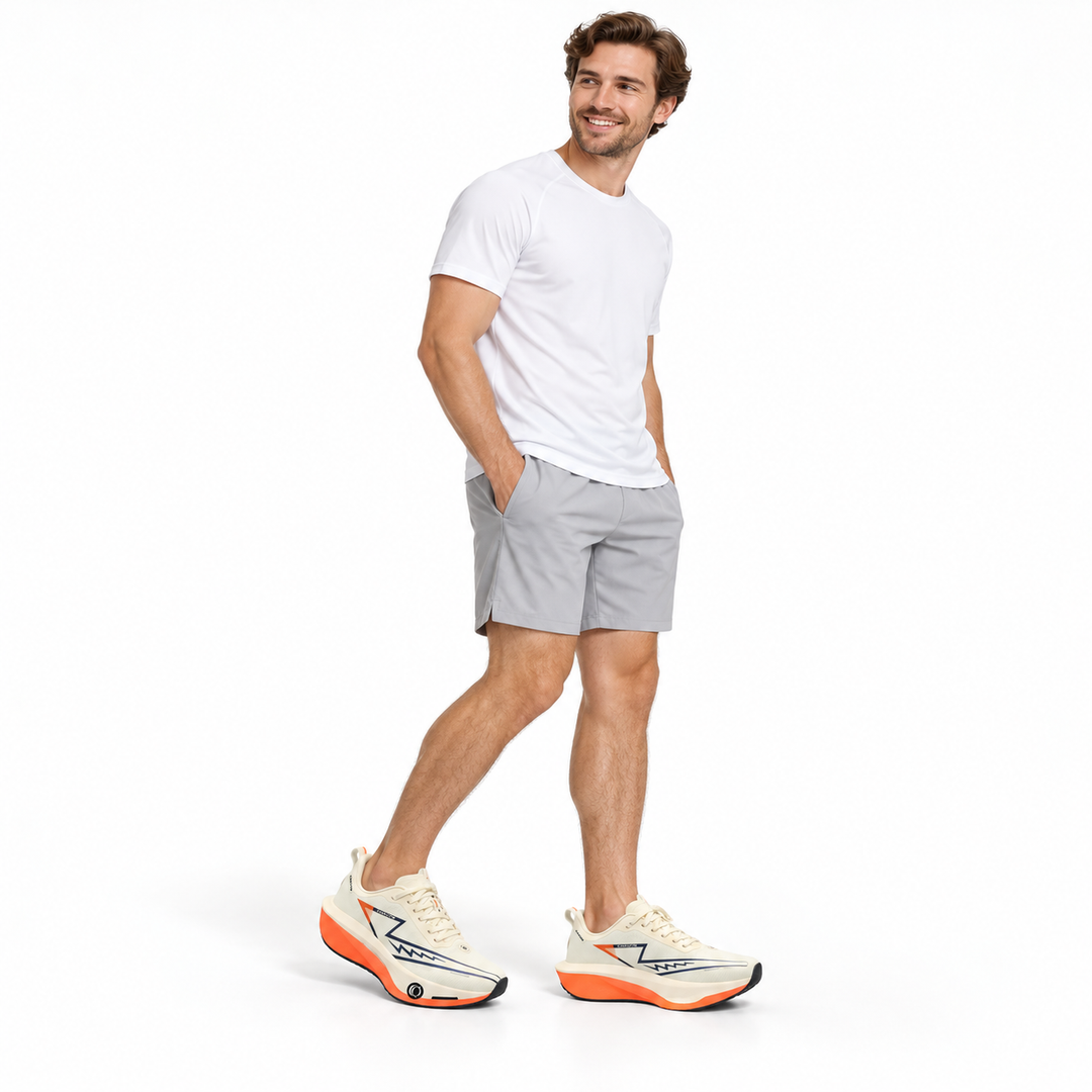 Male model wearing beige and orange lace-up sneakers on a white studio background.