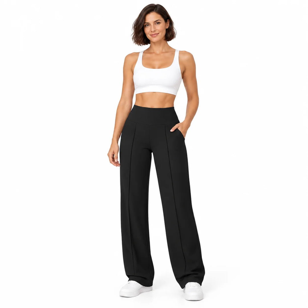 Black trousers worn by a full-body brunette model in a white studio, showing the high waistband, curved pockets and long legs