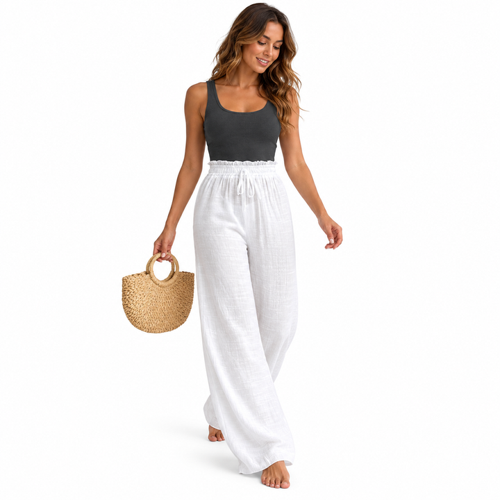 White crinkle trousers styled with a charcoal tank and woven bag on a walking model