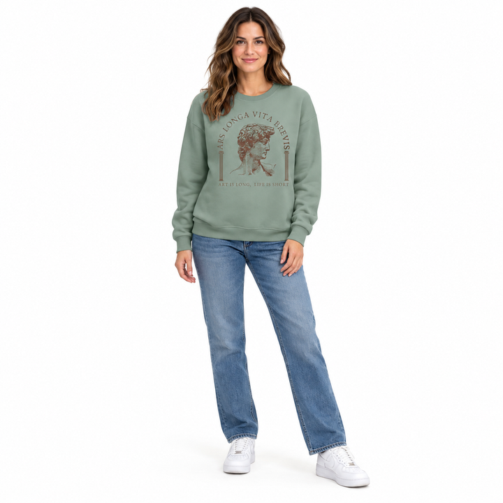 Olive green sweatshirt on a full-length model, with the brown classical head print, blue jeans and white shoes on a white set